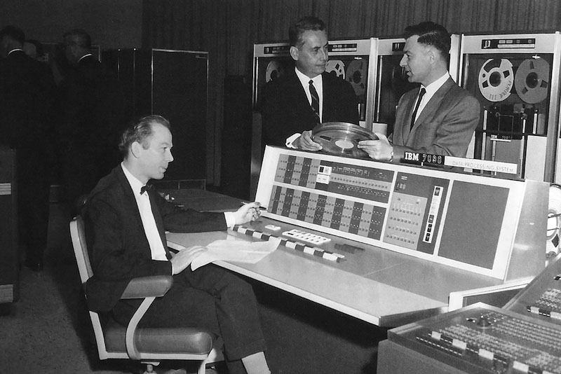 L. Duane Pyle seated at the console of the IBM 7090 with Samuel Conte standing on right during the 7090 dedication, April 26, 1963.