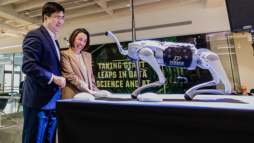 Purdue President Mung Chiang and Lucy Flesch, the Frederick L. Hovde Dean of the College of Science, celebrate with Robodog on Friday (Oct. 18) during dedication ceremonies for the university’s new Hall of Data Science and AI. (Purdue for Life Foundation photo/Gerry Robiños)