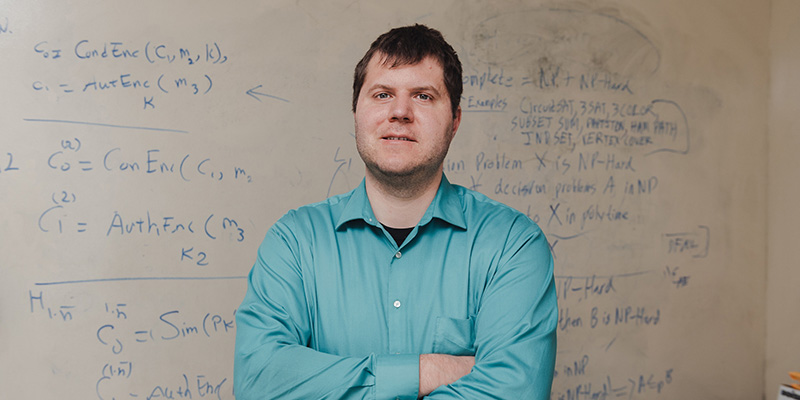 Jeremiah Blocki, an associate professor of computer science at Purdue, stands in front of a whiteboard of cryptography research in his office. Blocki’s work with passwords and secure systems is finding new and better ways to store information as securely as possible. (Purdue University photo/Greta Bell)