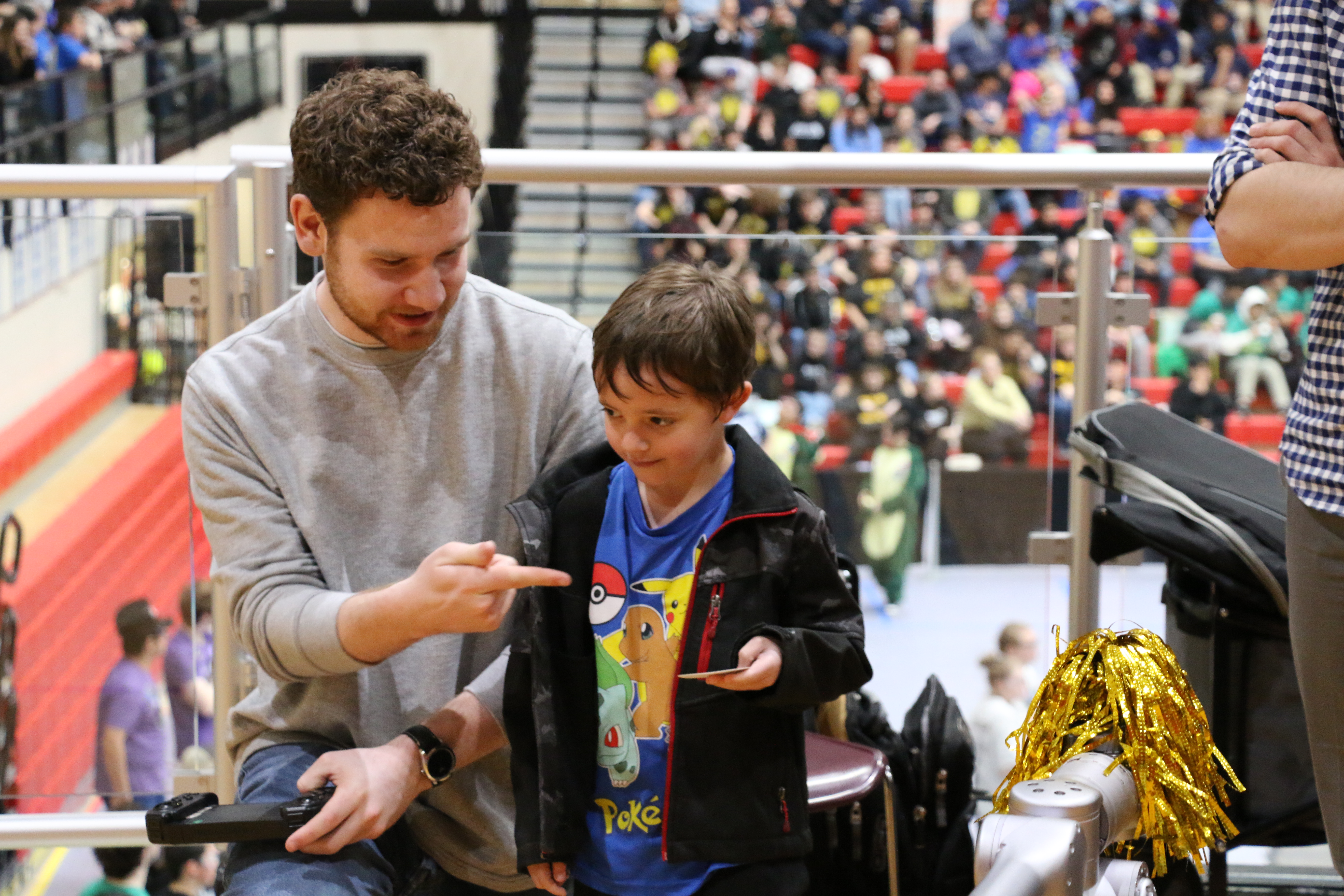 Undergraduate student, Thomas Peterson demonstrating the controls for a quadruped robot to a child.